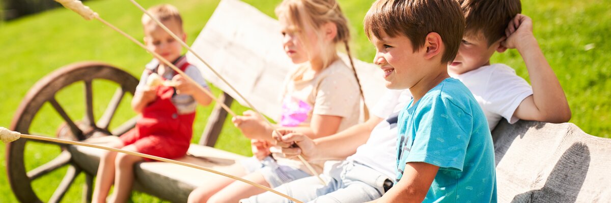 Kinder sitzen am Lagerfeuer und Grillen Stockbrot am Praschhof. | © Urlaub am Bauernhof/punktundkommagmbh