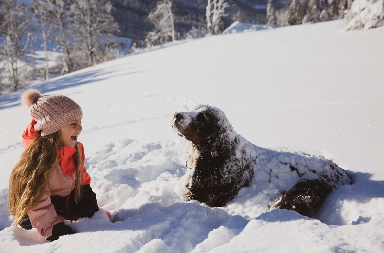 Mädchen spielt mit Hund im Schnee am Proneben Gut in Mühlbach am Hochkönig | © Urlaub am Bauernhof / Punkt & Komma