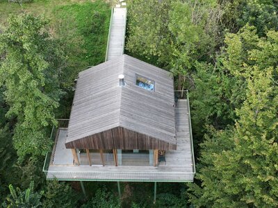 Baumhaus Buchengrün - wohnen auf Baumhöhe in der Nähe von Graz | © Familie Fröhlich-Graz / Nebel Baumhaus aus Holz mit Terrasse runderhum, fotografiert aus Vogelperspektive, umgeben von grünen Bäumen | © Familie Fröhlich-Graz / Nebel