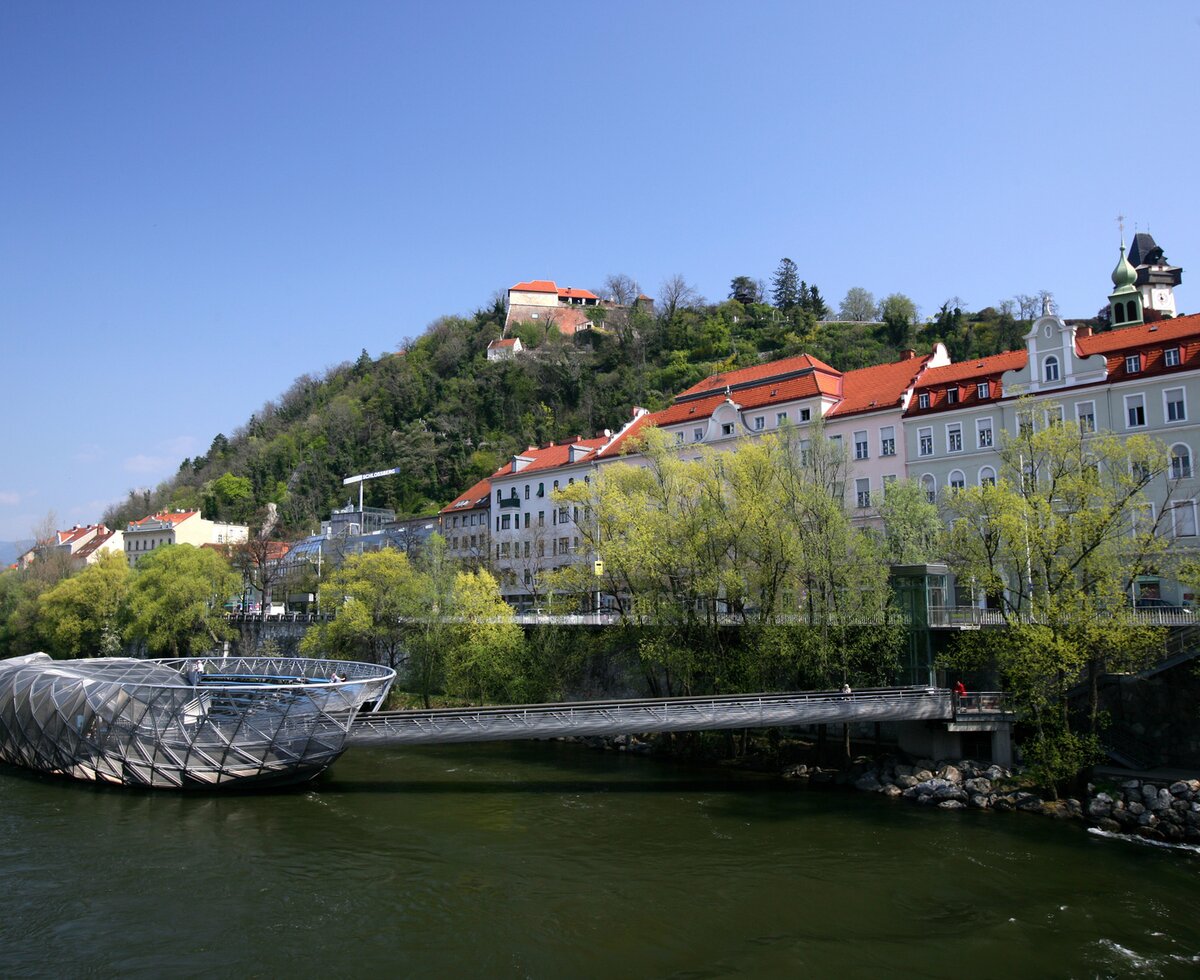 Die Murinsel in Graz, Steiermark | © Graz Tourismus / Harry Schiffer Die Murinsel und der Schloßberg in Graz, Steiermark | © Graz Tourismus / Harry Schiffer