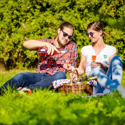 Ein paar sitzt im Weingarten beim Picknick und schenkt sich Schilcherfrizzante ein, Süd-West-Steiermark, Steiermark | © Urlaub am Bauernhof Steiermark / Wolfgang Spekner