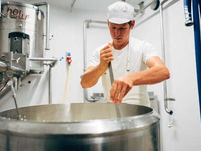Landwirt Thomas schneidet den Käsebruch mit der Käseharfe | © Urlaub am Bauernhof Vorarlberg / Daniel Gollner Landwirt Thomas bei der Käseherstellung | © Urlaub am Bauernhof Vorarlberg / Daniel Gollner