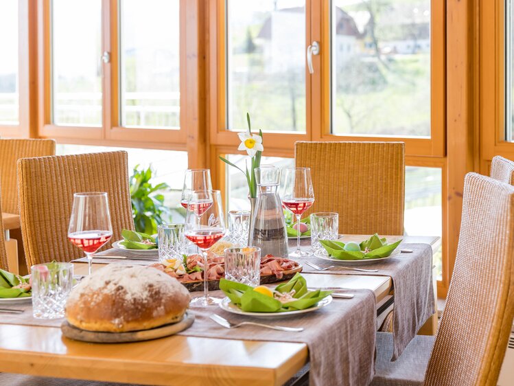 Ein gedeckter Tisch mit einer Osterjause, Frühlingsdekoration und vier Gläsern Wein. | © Urlaub am Winzerhof / ELISABETH FRÖHLICH photography