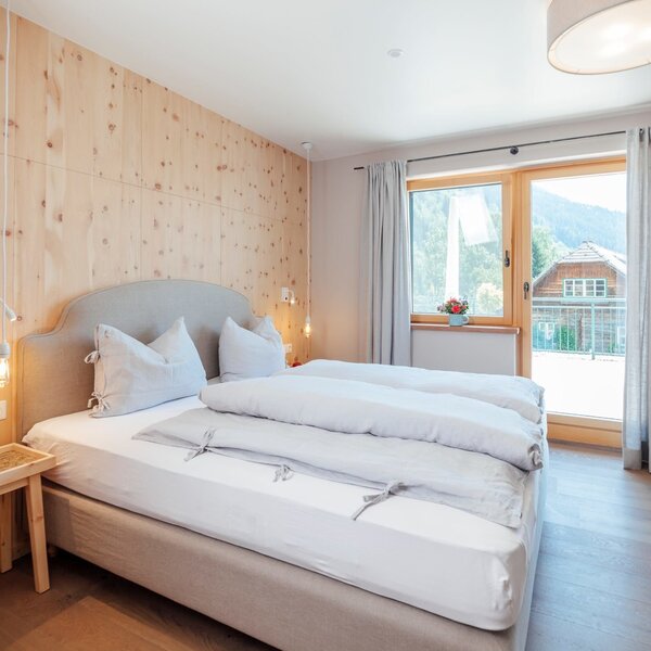 Double bedroom in the Farm House featuring wooden paneling, parquet flooring, a furnished balcony, and satellite TV.