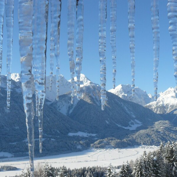 The winter mountain and valley view from the Farm House, featuring icicles in the foreground.