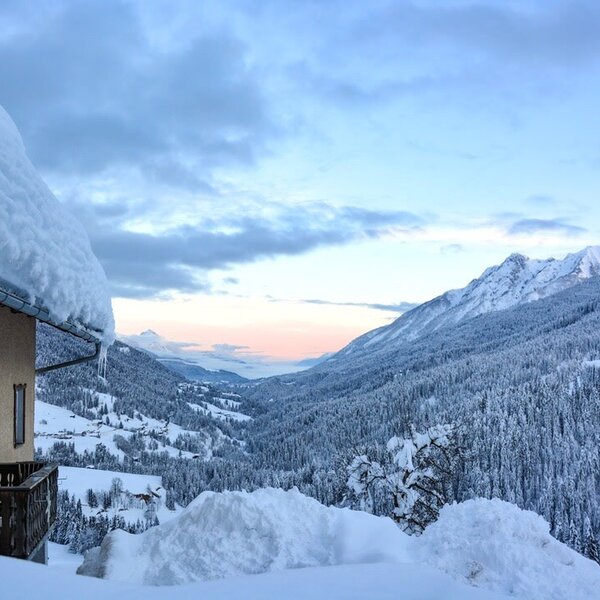 Panoramablick vom Bauernhof auf das verschneite Lesachtal und die umliegenden Berge.