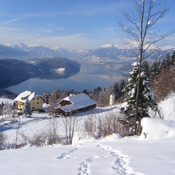 The Farm House in a snow-covered landscape, offering views of Lake Millstätter See and distant mountains.