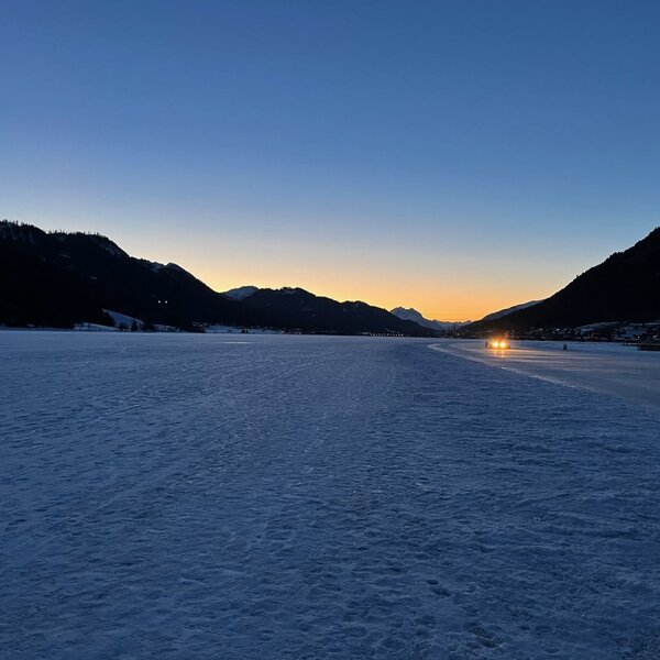 View of the frozen lake and surrounding mountains at sunset, characteristic of the Farm House's location.