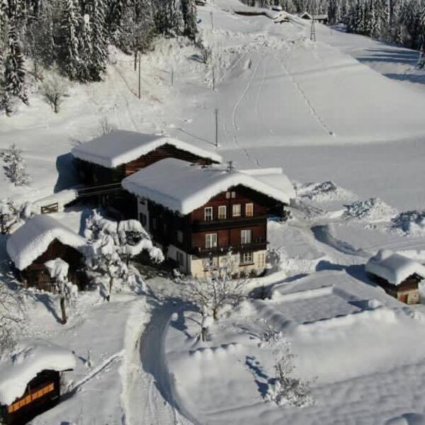 The Farm House and its snow-covered buildings, situated in a winter landscape with nearby ski tracks.