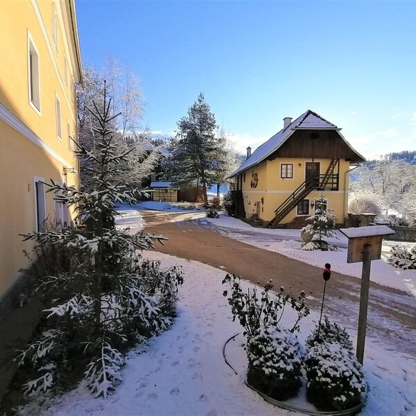 Der Bauernhof im Winter mit verschneiten Gebäuden und Außenbereich.