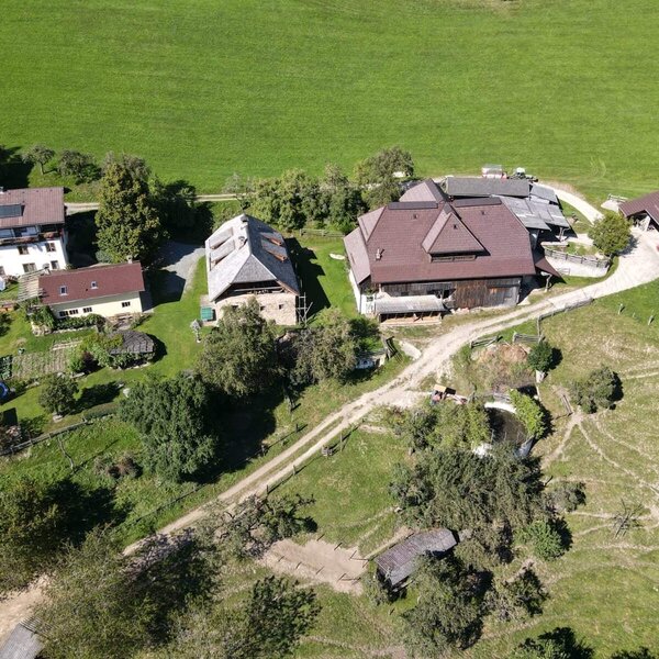 The Farm House complex, set amidst green fields, features several buildings and a small pond.