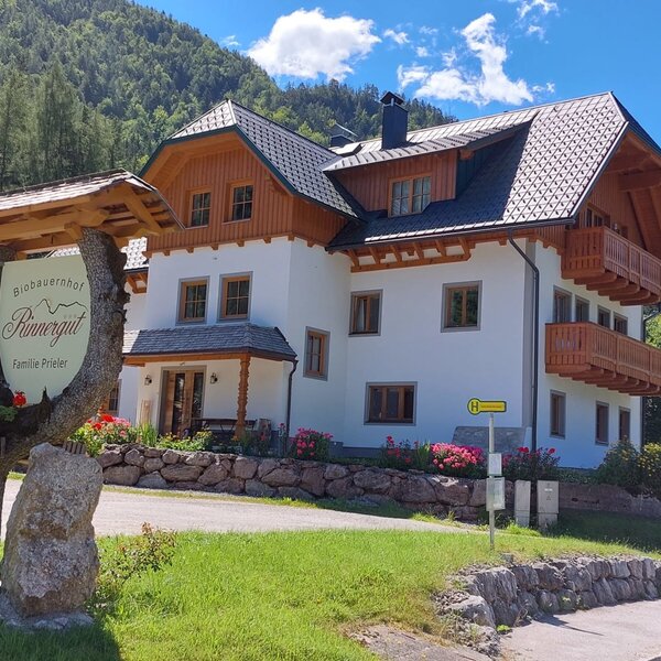 Außenansicht des Bauernhofs Rinnergut mit Holzbalkonen und dem Schild 'Biobauernhof Rinnergut Familie Prieler'.