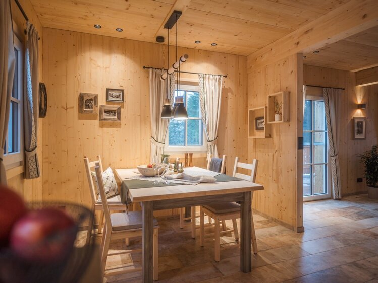 Essbereich im Hof mit Holztisch und vier Stühlen, umgeben von holzgetäfelten Wänden und einem Fenster.