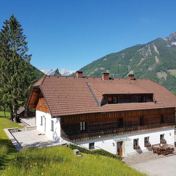 The Farm House, featuring a white and wooden exterior, outdoor terraces with a picnic table, and surrounding mountain views.