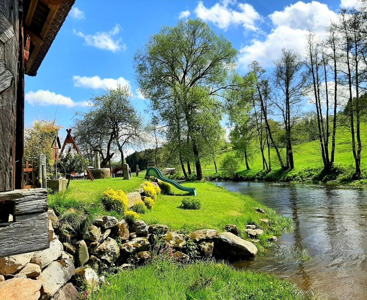 Gartenbereich des Bauernhofs am Fluss mit Rutsche und Spielgeräten.