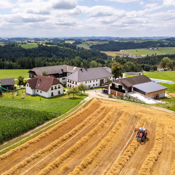 Aerial view of the farmhouse with its buildings, a tractor in the fields, and a playground. ©TVB Mühlviertel Berlinger Justin