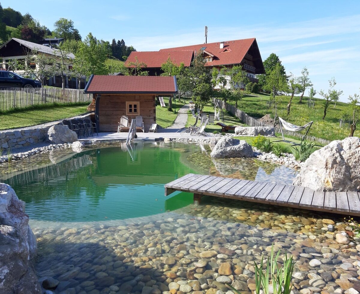 Schwimmteich mit Steg, im Hintergrund der Hochserner-Hof