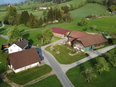 Aerial view of Biohof Grubbauer, a farm with multiple buildings and surrounding green fields.