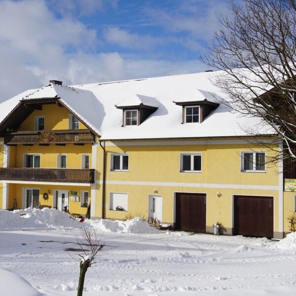 The Farm House exterior with a snow-covered roof and ground, featuring upper-floor balconies and dormer windows.