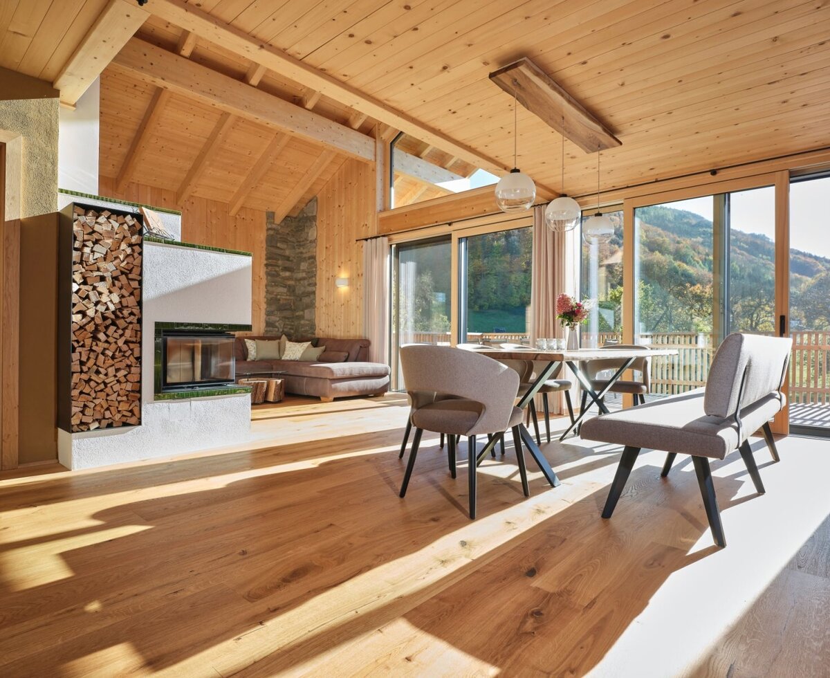 Wohnbereich des Chalets mit Kamin, Essbereich und Zugang zu Balkon mit Bergblick.