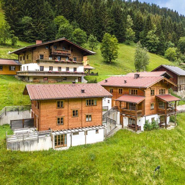 The inviting farmhouse is nestled among lush green meadows and forested mountain slopes.