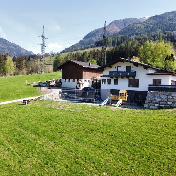 The farm house offers a trampoline and children's playground with mountains in the background.