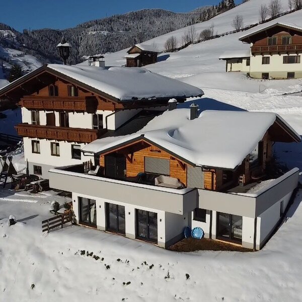 Der Bio Bauernhof Oberbenk im Winter, mit schneebedeckten Gebäuden und umliegender Berglandschaft.