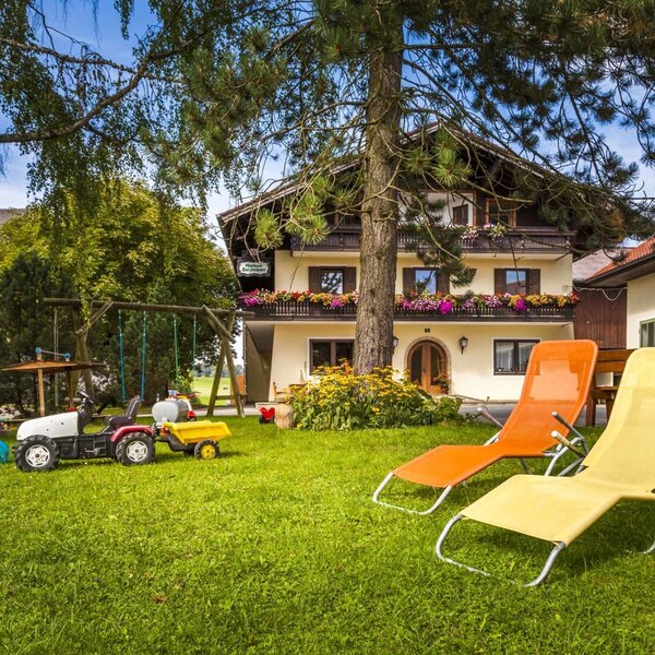 The farm house offers a garden with a children's swing set, a toy tractor, two sun loungers, and an outdoor dining area.