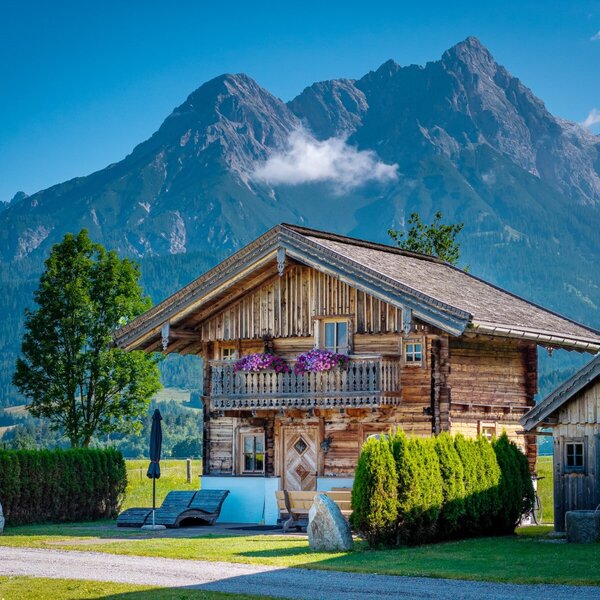 The chalet Steinerner Meerblick, featuring a balcony with flowers, an exclusive sauna hut, and sun loungers, all with mountain views.