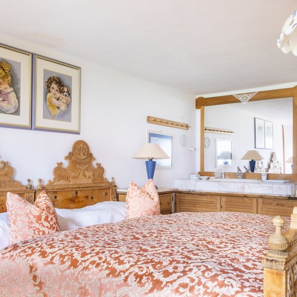 Double bedroom in the vacation rental featuring a carved wooden bed and a vanity area with a mirror and washbasin.