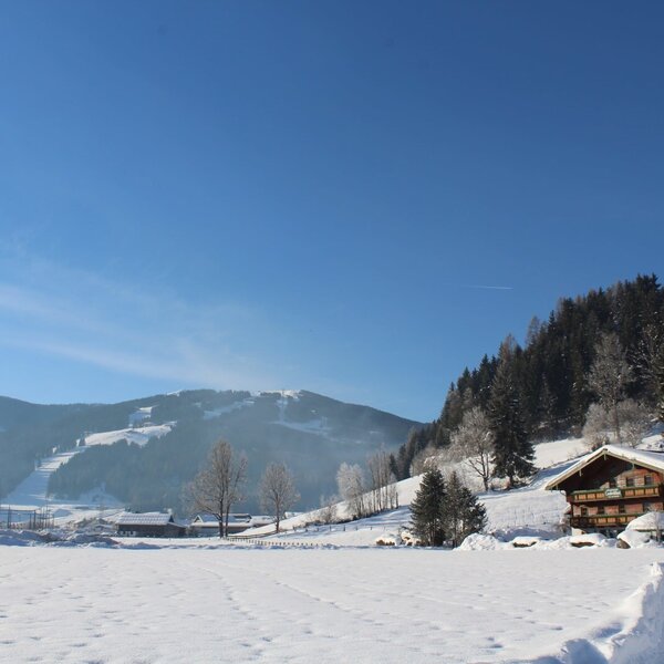 The Farm House in its winter setting, featuring snow-covered fields and mountains with visible ski slopes.