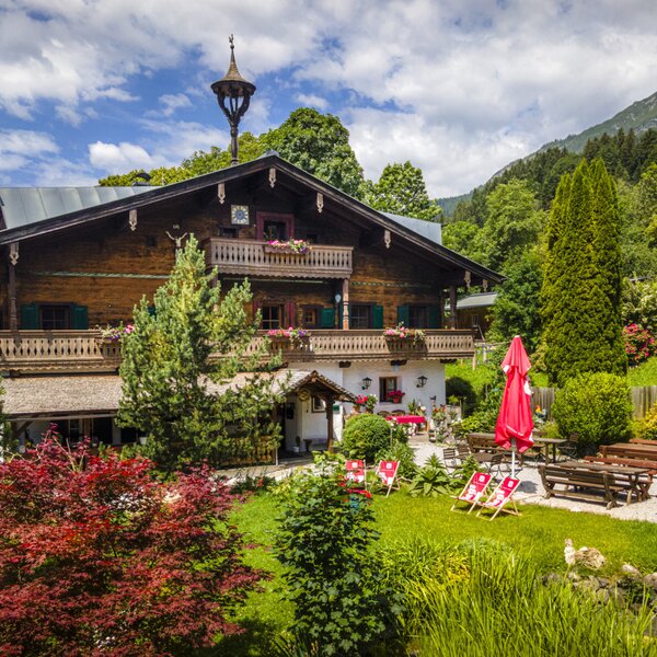 Der einladende Bauernhof mit einem gepflegten Garten, einer gemütlichen Terrasse und schattenspendenden Sonnenschirmen.