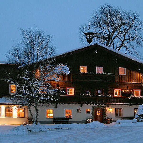 Der traditionelle Bauernhof, abends beleuchtet und von Schnee bedeckt.