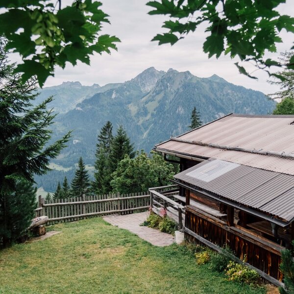 The farmhouse exterior, with its grassy yard and wooden fence, overlooks mountains and valleys.