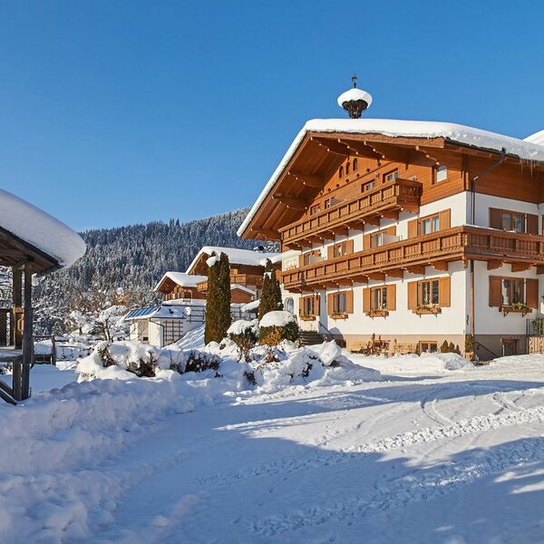 Der Bauernhof im Winter mit schneebedeckten Dächern und einem Holzpavillon auf dem Gelände. Der Bauernhof im Winter mit schneebedeckten Dächern und einem Holzpavillon auf dem Gelände.