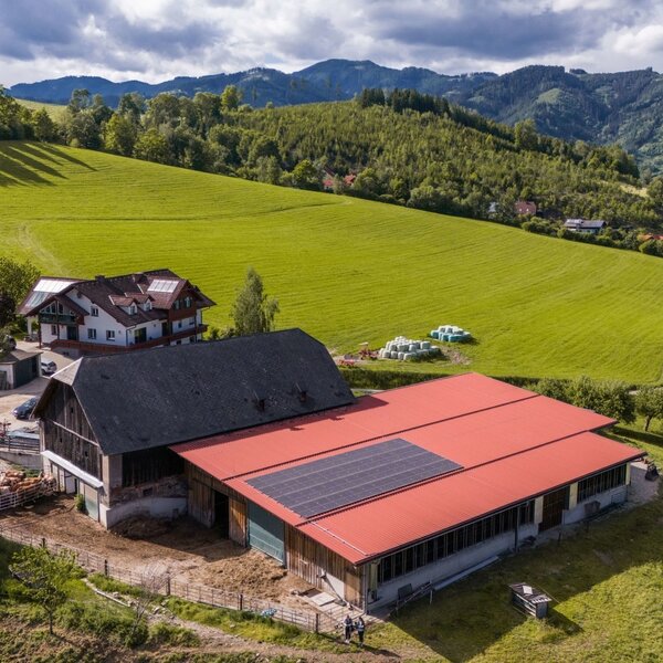 Luftaufnahme des Bauernhofs Retzmoar mit seinen Gebäuden, den umliegenden Wiesen und der Berglandschaft.
