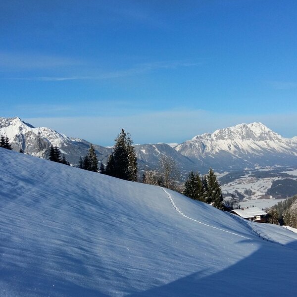 A winter landscape featuring snow-covered slopes, distant mountain peaks, and a valley, representing the surroundings of the Farm House.