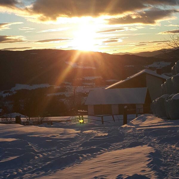 Sunset view over snow-covered fields and mountains from the farm house.