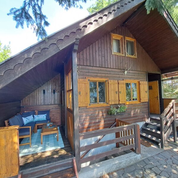 Die charmante Almhütte im rustikalen Holzstil mit einer gemütlichen, überdachten Terrasse.