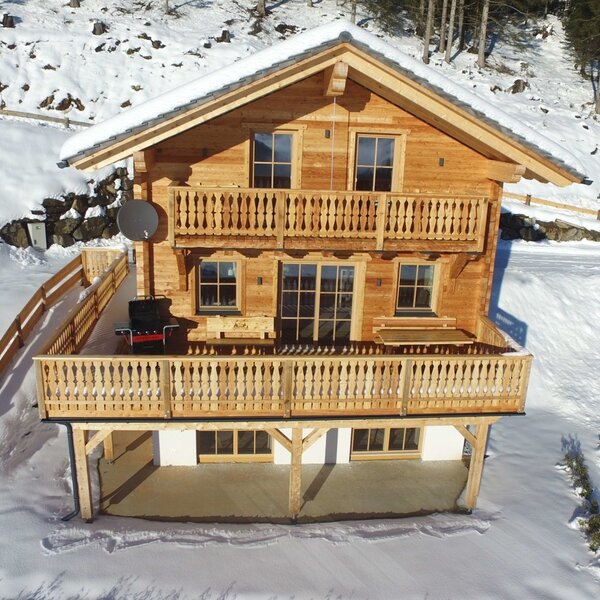 Die Hütte ist aus Holz gebaut, von Schnee umgeben und verfügt über zwei Balkone mit Holzgeländern.