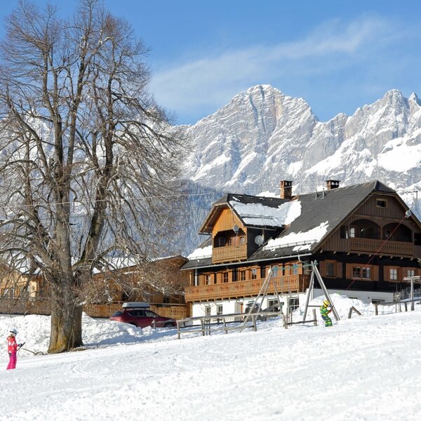 Der Bauernhof im Winter, gelegen an einer Skipiste mit Blick auf die umliegende Bergwelt.