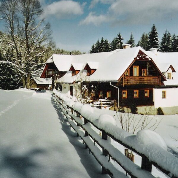 Der schneebedeckte Bauernhof mit Holzbalkonen und Gauben im Winter.