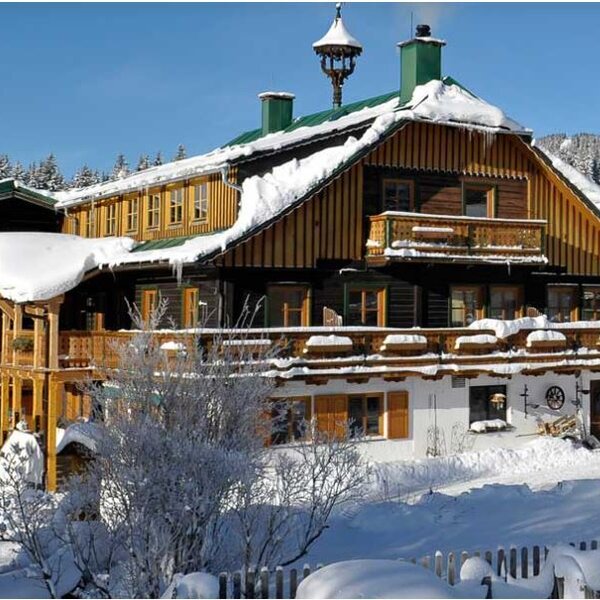 The Farm House features snow-covered roofs and balconies, showcasing its traditional wooden design in a winter setting.