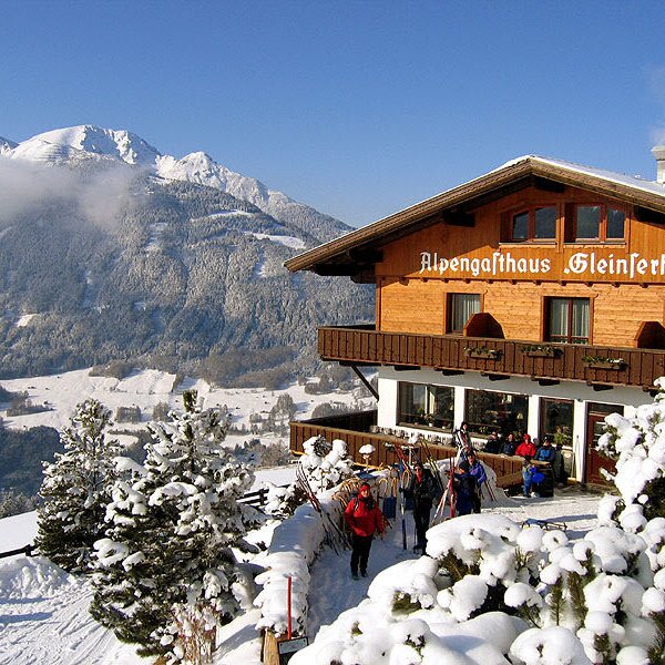Das Alpengasthaus Gleinserhof des Bauernhofs in winterlicher Berglandschaft, mit Skifahrern am Eingang.