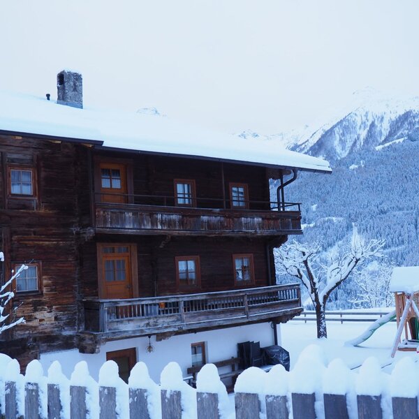 The Farm House exterior features snow-covered balconies, a children's playground, and mountain views.