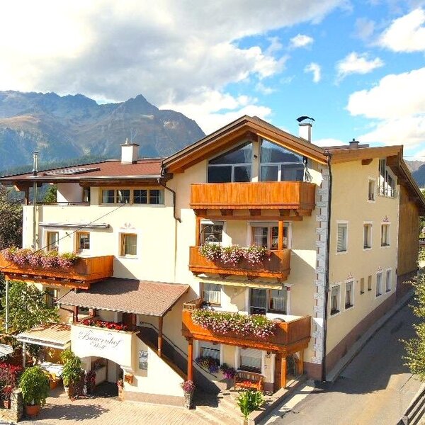 Außenansicht des Bauernhofs mit Balkonen, Blumenkästen, Sonnenterrasse und Bergblick.