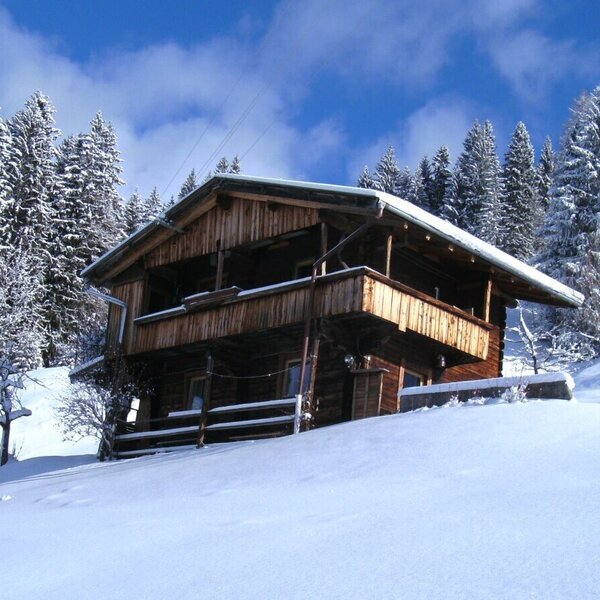 Die Alm im Winter, umgeben von Schnee und verschneiten Wäldern.
