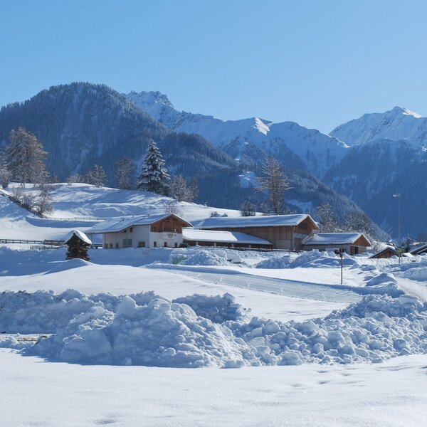 The Darrehof Farm House complex in a snow-covered valley with mountain views.