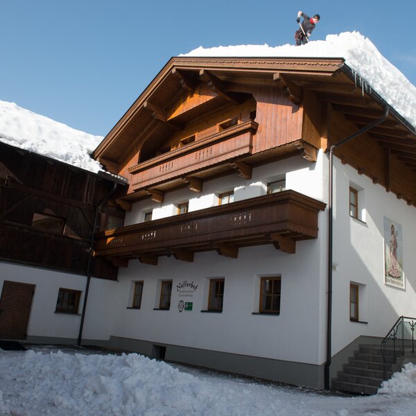 Die winterliche Außenansicht des Bauernhofs Natterhof mit schneebedeckten Dächern und Holzbalkonen.