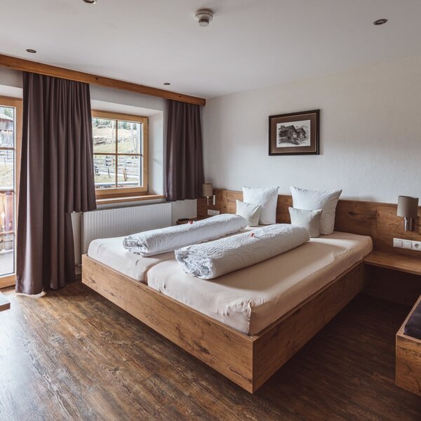 Double bedroom in the Farm House with a wooden bed, direct outdoor access, and windows overlooking the rural landscape.